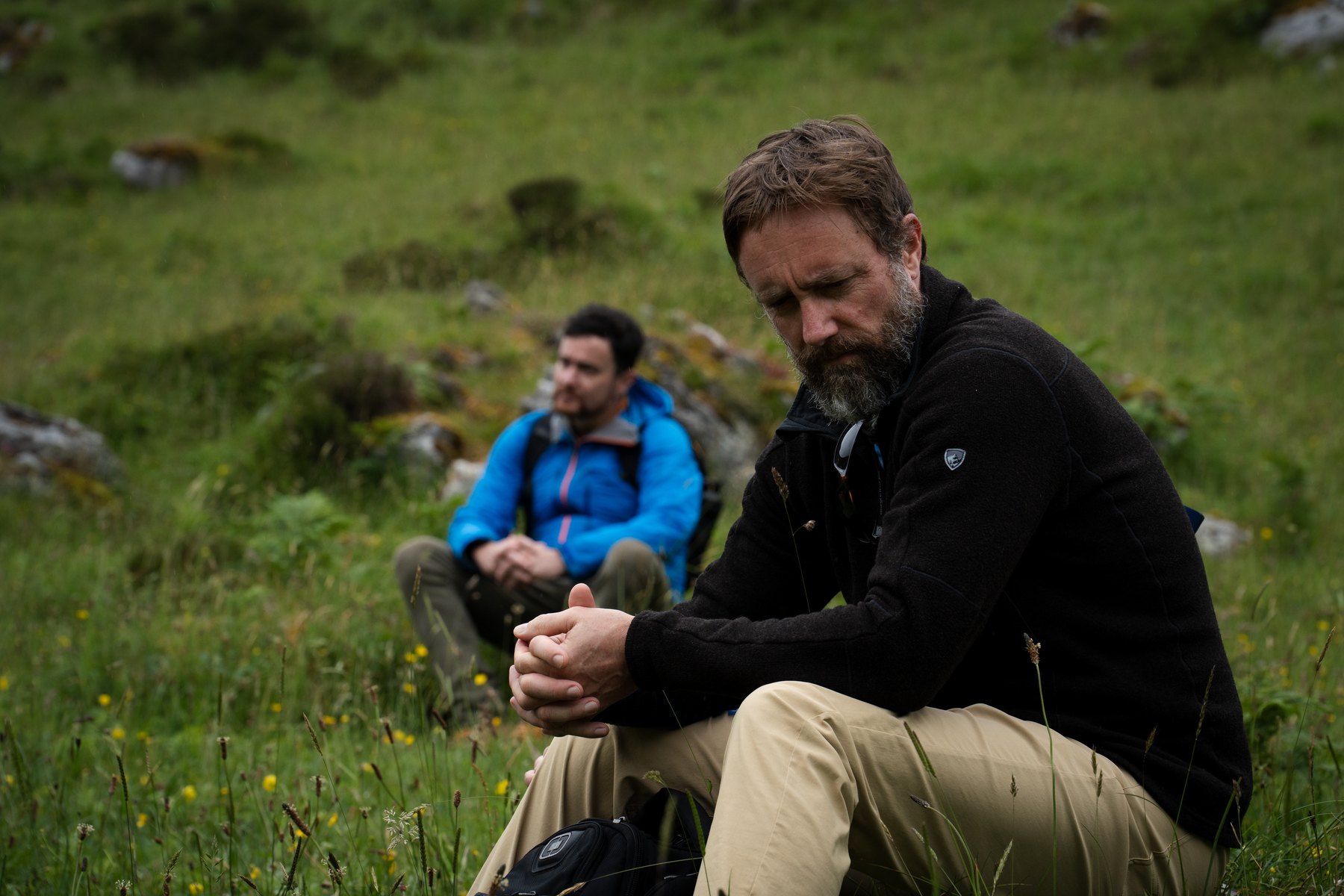 Chad Prevost seated on an Irish hillside, in thought, a companion behind